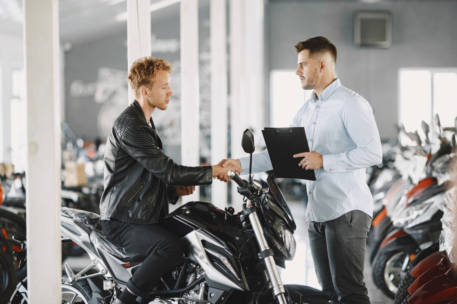 Homem aperta mão de vendedor durante compra de moto após saber como funciona consorcio de moto