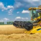 Colheitadeira realizando a colheita de trigo em uma lavoura, representando o consórcio de máquinas agrícolas