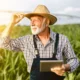 Produtor rural segurando tablet em plantação, representando investimentos com crédito rural e consórcio